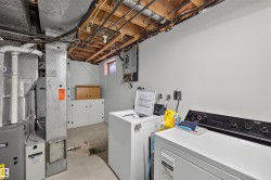Laundry area featuring built-in white cabinetry, exposed ceiling joists, and a utility window - 