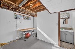 Recessed windows, exposed ceiling joists, and an adjoining bathroom featuring a vanity with an integrated sink - 