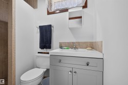 Recessed shower with mosaic tile surround, vanity with light gray cabinetry, integrated sink, and chrome faucet - 