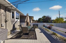 Spacious outdoor deck with light-toned decking, an integrated white fence, and a white trellis planter box - 
