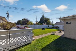 Expansive backyard featuring a manicured lawn, paver patio, and white privacy fencing - 