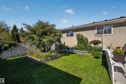 Grassed backyard with a raised garden bed, chain link fencing, and a private deck - 