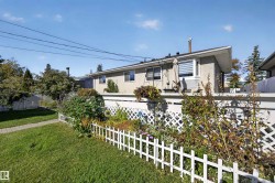 Manicured lawn with a paver pathway, framed by a white picket fence and mature landscaping - 