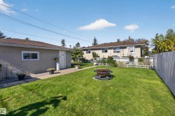 Expansive backyard with a manicured lawn, paved walkway, and a fire pit - 