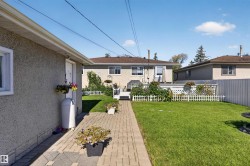 Expansive backyard featuring a green lawn, brick paver pathway, white picket fencing, and a rear deck - 