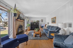 Light wood-finish flooring throughout, brick fireplace with a wood mantle, and a built-in electric insert - 