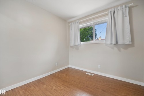 Room featuring wood-finish flooring, white walls, and a white-framed window - 13420 117 Avenue Nw, Edmonton, AB 