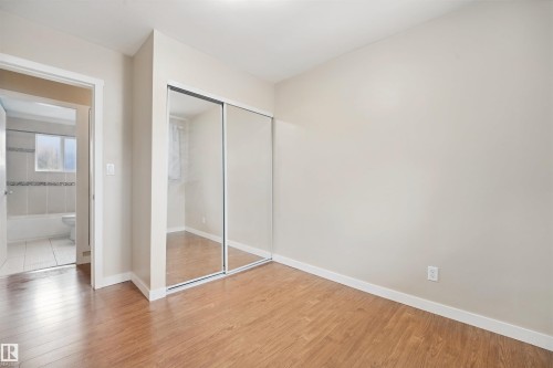 Wood-finish flooring, sliding mirrored closet doors, and light-toned walls - 13420 117 Avenue Nw, Edmonton, AB 