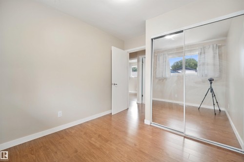 Wood-finish flooring, mirrored sliding closet doors, neutral wall paint, and white trim - 13420 117 Avenue Nw, Edmonton, AB 