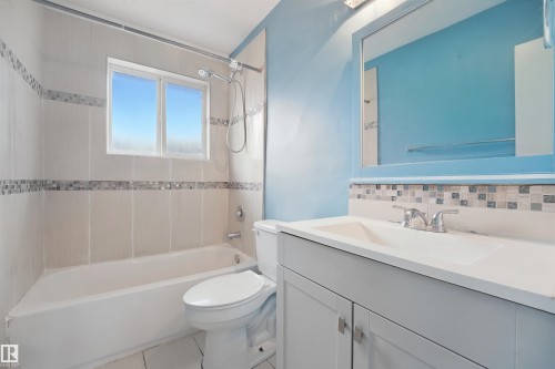 Bathroom featuring a white vanity with integrated sink, chrome fixtures, mosaic tile backsplash, and a tiled shower/tub combination - 13420 117 Avenue Nw, Edmonton, AB 