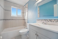 Bathroom featuring a white vanity with integrated sink, chrome fixtures, mosaic tile backsplash, and a tiled shower/tub combination - 