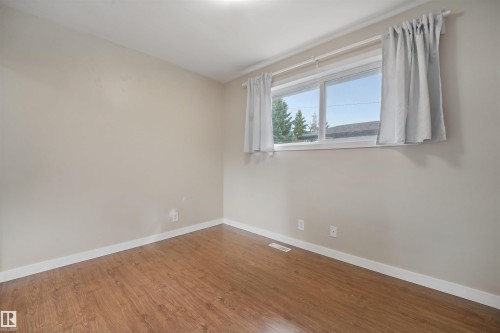 Wood-finish flooring, neutral wall tones, and a bright window with white trim - 13420 117 Avenue Nw, Edmonton, AB 