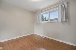 Wood-finish flooring, neutral wall tones, and a bright window with white trim - 
