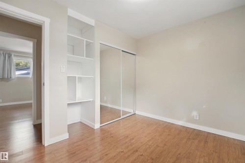 Wood-finish flooring, built-in shelving, mirrored sliding closet doors, and light neutral wall paint - 13420 117 Avenue Nw, Edmonton, AB 