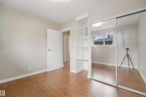 Wood-finish flooring throughout, bright window, mirrored sliding closet doors, and built-in shelving - 13420 117 Avenue Nw, Edmonton, AB 