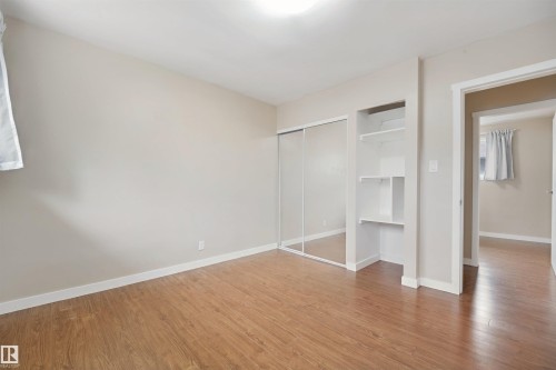 Wood-finish flooring with white trim, mirrored closet doors, and built-in shelving - 13420 117 Avenue Nw, Edmonton, AB 