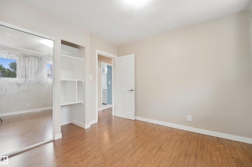 Wood-finish flooring, neutral wall tones, a built-in shelving unit, and mirrored closet doors - 13420 117 Avenue Nw, Edmonton, AB 