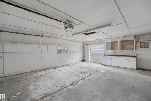 Spacious garage with concrete flooring, built-in cabinetry, and multiple windows for natural light - 13420 117 Avenue Nw, Edmonton, AB 