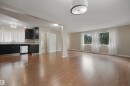 Expansive wood-finish flooring throughout, multiple large windows, recessed lighting, and a modern kitchen with dark cabinetry and stainless steel appliances - 13420 117 Avenue Nw, Edmonton, AB 