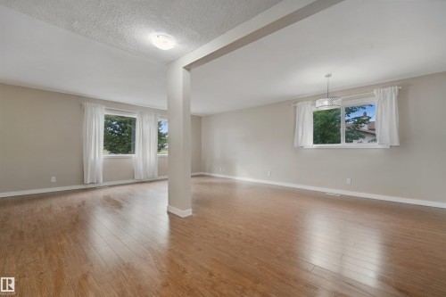 Expansive room featuring wood-finish flooring, neutral-toned walls, and multiple windows - 13420 117 Avenue Nw, Edmonton, AB 