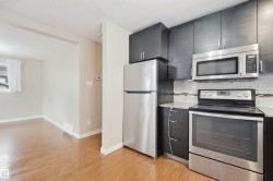 Kitchen featuring dark cabinetry, stainless steel appliances, a white subway tile backsplash, and light-toned countertops - 