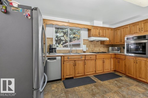 Wood-finish cabinetry, stainless steel appliances, durable tile flooring, and integrated wall oven - #74 22555 Twp Road 530, Rural Strathcona County, AB 