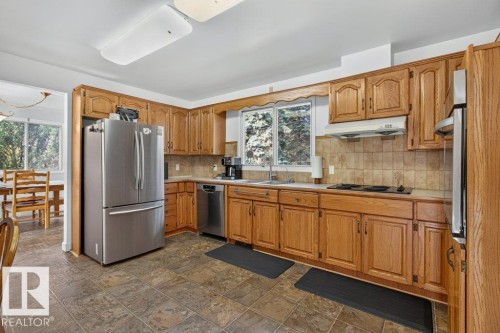 Kitchen featuring wood cabinetry, stainless steel appliances, tiled flooring, and a tiled backsplash - #74 22555 Twp Road 530, Rural Strathcona County, AB 