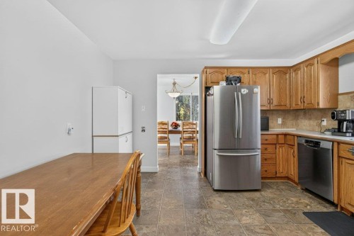 Kitchen featuring wood cabinetry, stainless steel refrigerator, stainless steel dishwasher, and tiled flooring - #74 22555 Twp Road 530, Rural Strathcona County, AB 