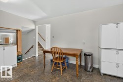 Tiled flooring throughout, white cabinetry with silver hardware, and a staircase with wood-finish handrails - 