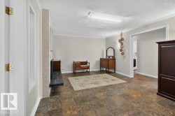 Spacious room featuring tile flooring, crown molding, and a light brick fireplace with a dark stone hearth - 