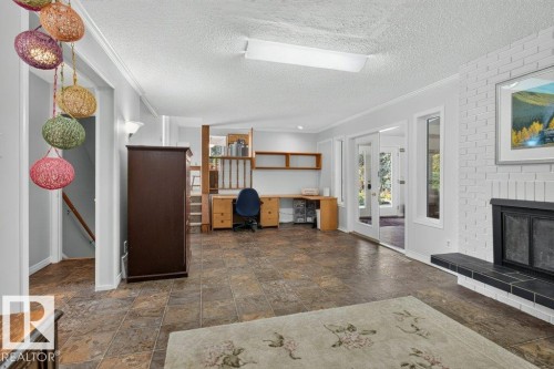 Spacious interior featuring a white brick fireplace with a black hearth, built-in shelving, and large sliding glass doors - #74 22555 Twp Road 530, Rural Strathcona County, AB 