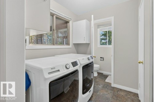 Laundry area featuring tiled flooring, upper white cabinetry, and a window with blinds - #74 22555 Twp Road 530, Rural Strathcona County, AB 