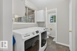 Laundry area featuring tiled flooring, upper white cabinetry, and a window with blinds - 