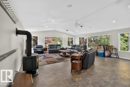 Spacious living area featuring large windows, a ceiling fan, recessed lighting, and a freestanding stove with a flue - #74 22555 Twp Road 530, Rural Strathcona County, AB 
