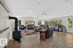 Spacious living area featuring large windows, a ceiling fan, recessed lighting, and a freestanding stove with a flue - 