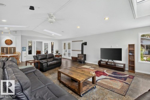 Spacious living area featuring a wood-burning stove, tiled flooring, recessed lighting, and a ceiling fan - #74 22555 Twp Road 530, Rural Strathcona County, AB 