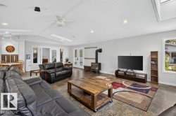 Spacious living area featuring a wood-burning stove, tiled flooring, recessed lighting, and a ceiling fan - 