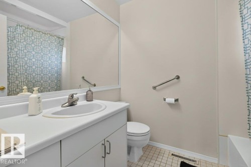 Bathroom featuring a vanity with an integrated sink, a large wall-mounted mirror, a toilet, and a bathtub with grab bar - #74 22555 Twp Road 530, Rural Strathcona County, AB 