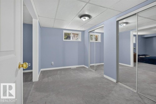Gray carpeting, light blue wall paint, white trim, sliding mirrored closet doors, and a drop ceiling - #74 22555 Twp Road 530, Rural Strathcona County, AB 