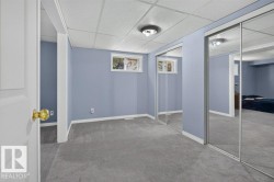 Gray carpeting, light blue wall paint, white trim, sliding mirrored closet doors, and a drop ceiling - 