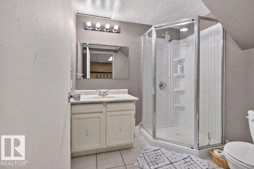 Corner shower enclosure, single vanity with integrated sink, wall-mounted mirror, and tile flooring - #74 22555 Twp Road 530, Rural Strathcona County, AB 