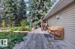 Exterior wood-finish decking with a light-colored vinyl-sided wall and a built-in light fixture - 
