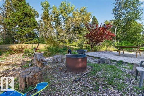 Gravel hardscaping with a fire pit, wood stump seating, and a wood deck - #74 22555 Twp Road 530, Rural Strathcona County, AB 