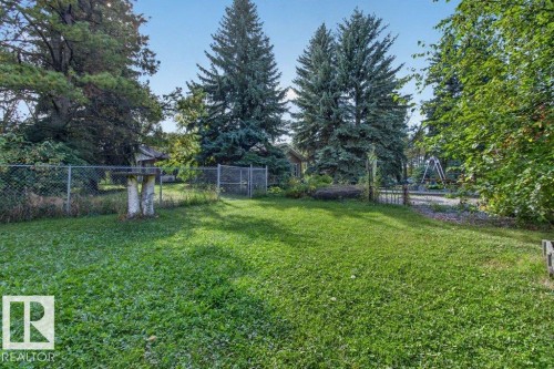 Expansive lawn area surrounded by mature trees, featuring chain-link fencing - #74 22555 Twp Road 530, Rural Strathcona County, AB 