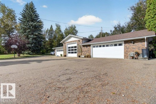 Brick exterior with multiple garage bays, one featuring a glass panel door and two with solid panel doors - #74 22555 Twp Road 530, Rural Strathcona County, AB 