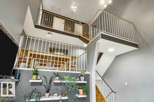 Multi-level interior featuring open railings, recessed lighting, wood-finish stairs, and a stone-clad fireplace - #24 3811 85 St Nw, Edmonton, AB 