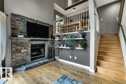 Wood-finish flooring with a stacked stone fireplace featuring a hearth - #24 3811 85 St Nw, Edmonton, AB 