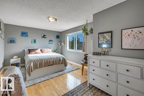 Hardwood flooring, painted walls, window with outdoor scenery, recessed lighting, and a white storage dresser with black hardware - #24 3811 85 St Nw, Edmonton, AB 