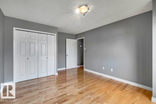 Wood-finish flooring, neutral gray wall tones, white trim, and a bi-fold closet - #24 3811 85 St Nw, Edmonton, AB 
