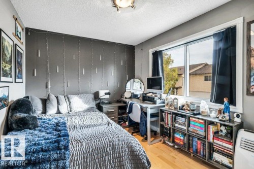 Wood-finish flooring, a large window, a built-in shelving unit, and a ceiling-mounted light fixture - #24 3811 85 St Nw, Edmonton, AB 